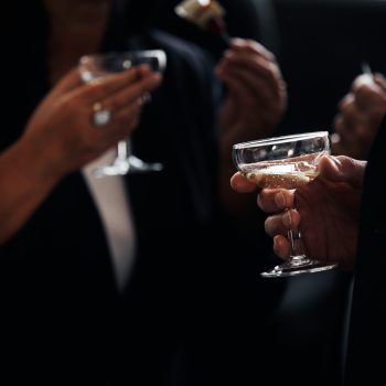 business meeting. successful people in stylish suits holding glasses of alcohol on party, corporate party, conference, forums, banquets, closeup. selective focus. hand with drink of Champagne.