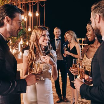 Group of people in formalwear communicating and smiling while spending time on luxury party